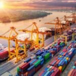 Aerial view of a busy container port with cranes loading cargo ships and stacked containers, representing large-scale logistics and global trade operations.