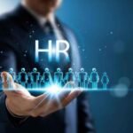 Business professional holding a digital HR interface with icons representing employees, symbolizing modern human resource management and workforce technology.