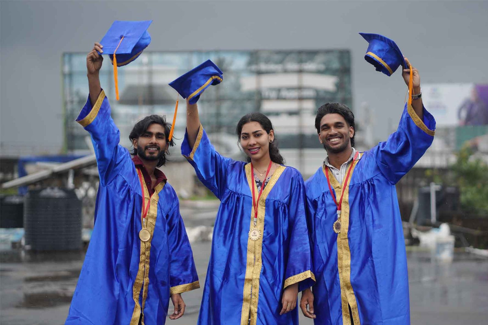 Graduates in blue caps and gowns celebrating with raised hats and medals outside the best logistics institute in kerala
