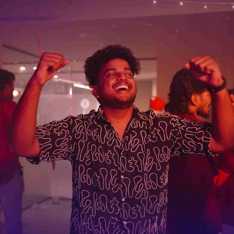 Young man celebrating with raised hands at a lively indoor event in the best logistics institute in kerala, representing student life and campus experience.