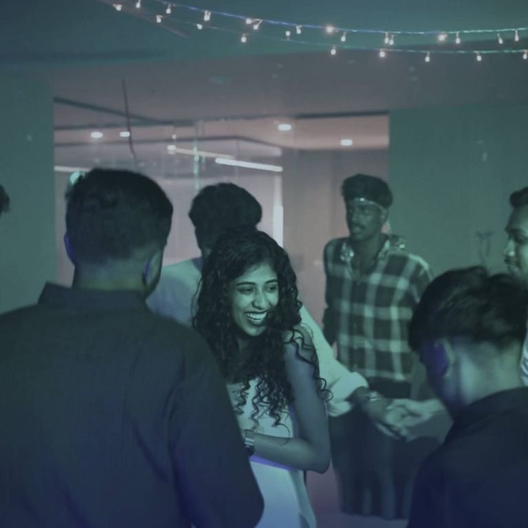 Students socializing and enjoying a lively indoor event under decorative lights in the best logistics institute in kerala, showcasing fun and interactive campus activities.